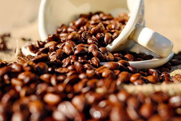 coffee cup filled with coffee beans tipped over