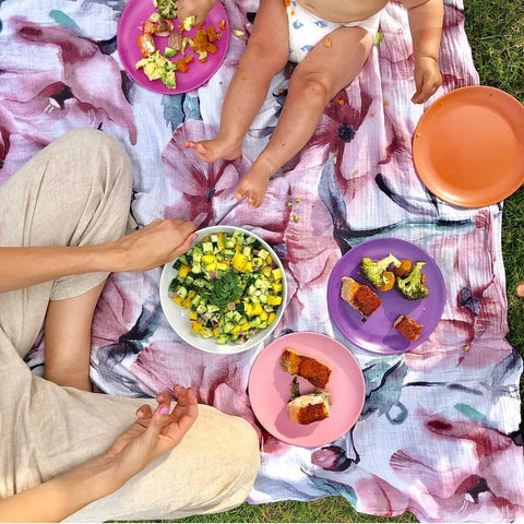 a mom and child eating healthy food on a picnic rug