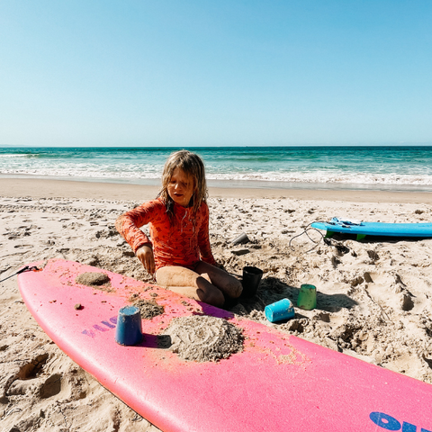 girl using our bamboo cups to play with sand on her surfboard