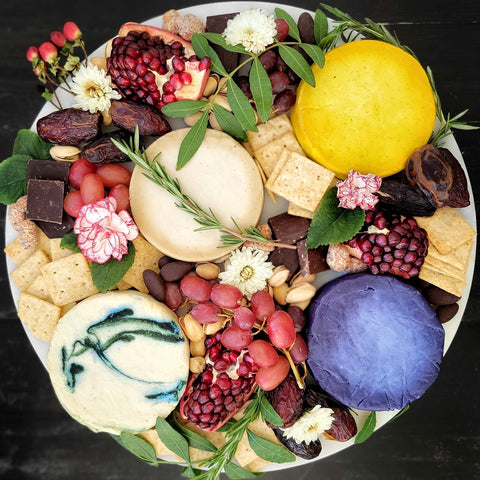 Round cheese board with a variety of cheese wheels on bountiful cheese board seen from above