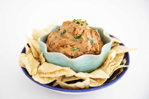 Bean dip in bowl with tortilla chips served around it