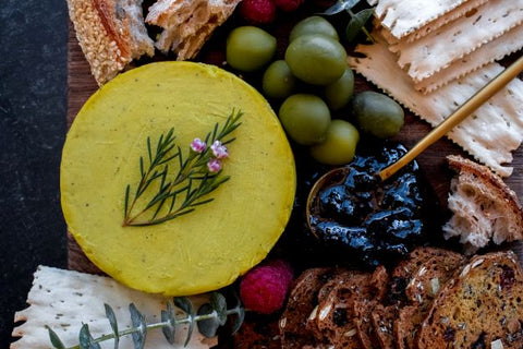 Yellow cheese on cheese board with condiments seen from above