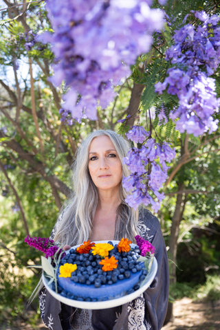 Woman serving blue cheese cake on platter with blueberries and flowers