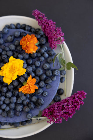 Close up image of blue cheese cake loaded with blueberries and flowers