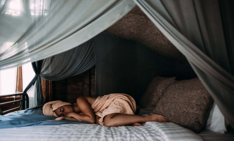 Eine Frau schläft auf einem Bett in einem traumhaftes Schlafzimmer