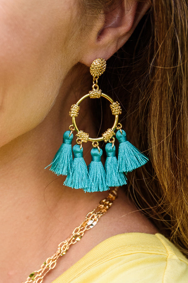 Close up of teal tassel earrings on a woman