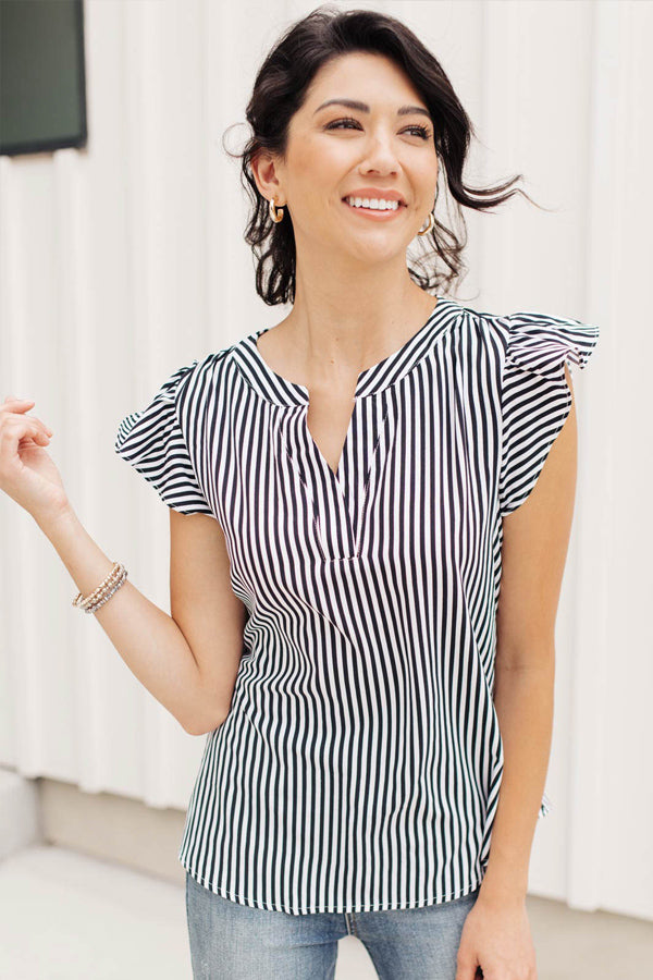 Woman smiling wearing a striped top with ruffly cap sleeves