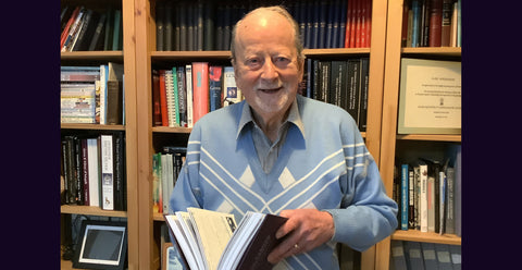 A photograph of Alan Hodgkinson holding his gemmology book Gem Testing Techniques