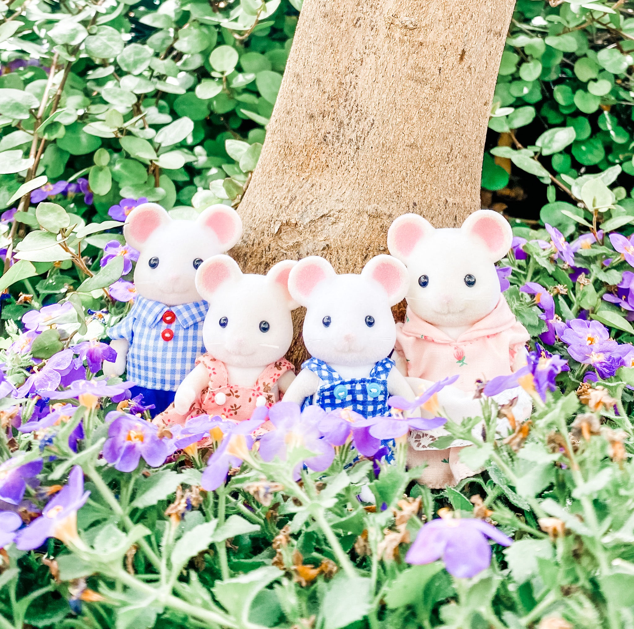 Calico Critters Hawthorn Mouse Family near a tree, surrounded by purple flowers