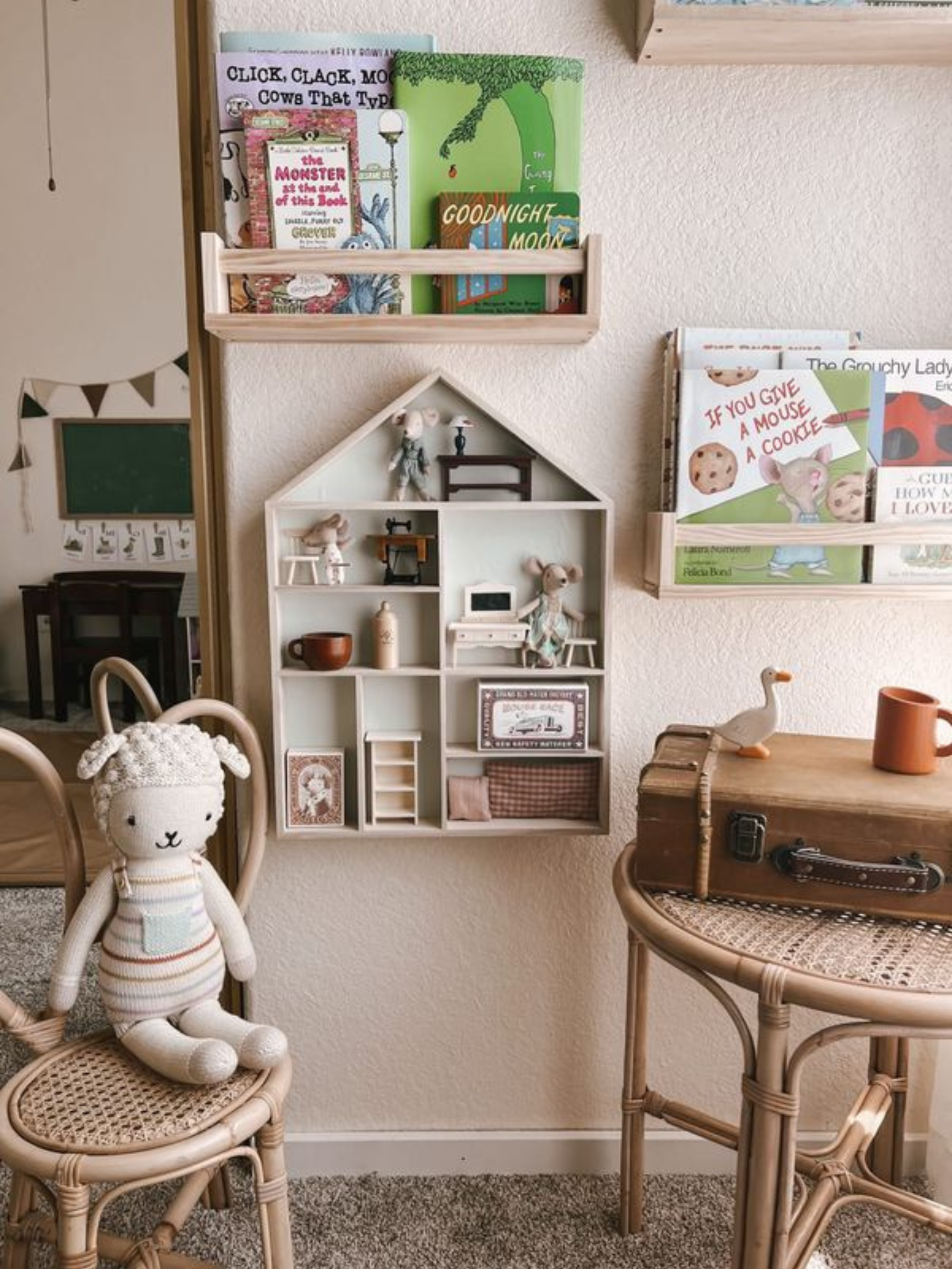 Floating bookshelves hung on a playroom wall near a house shaped display shelf.