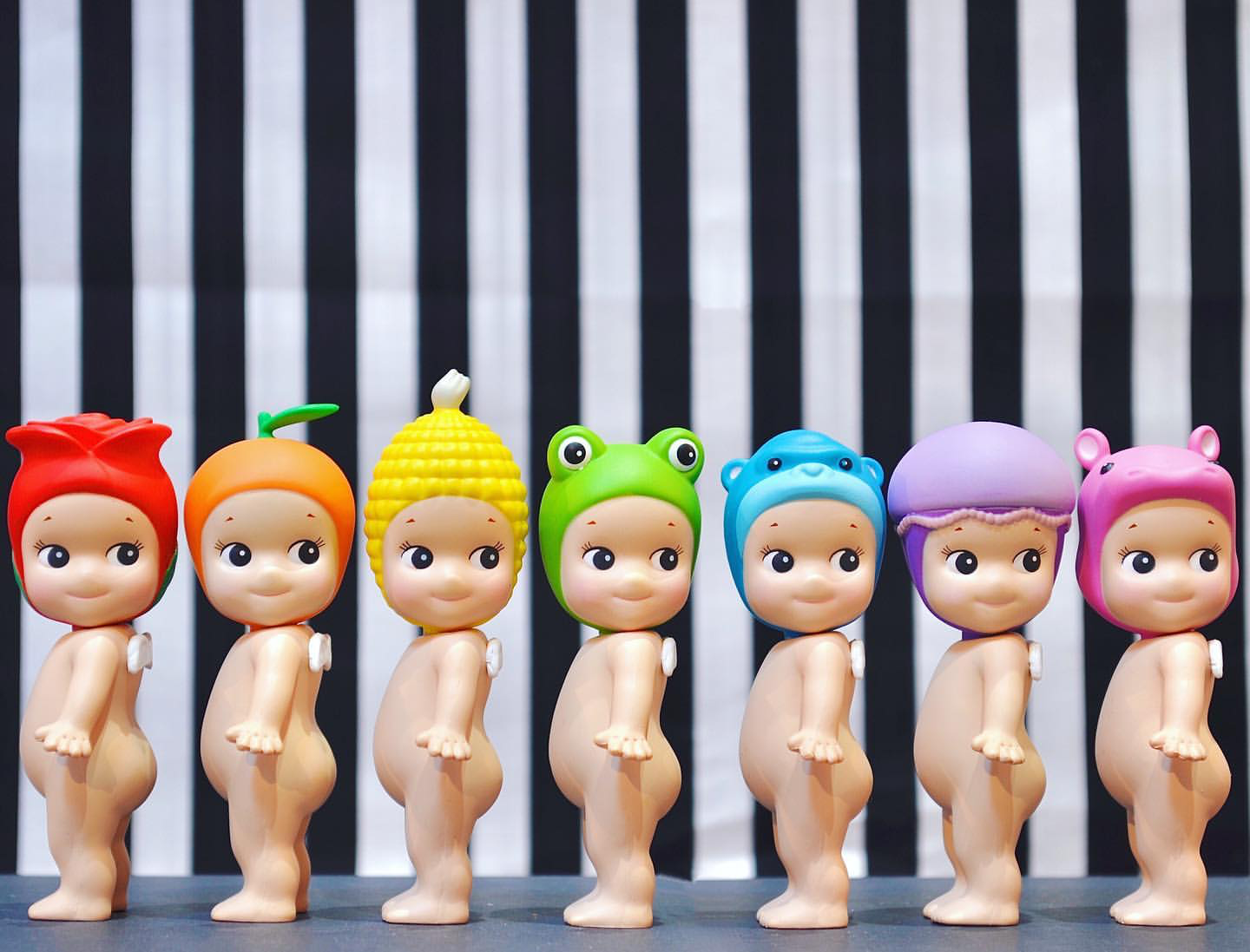 Sonny Angels standing in line making a rainbow with their head gear
