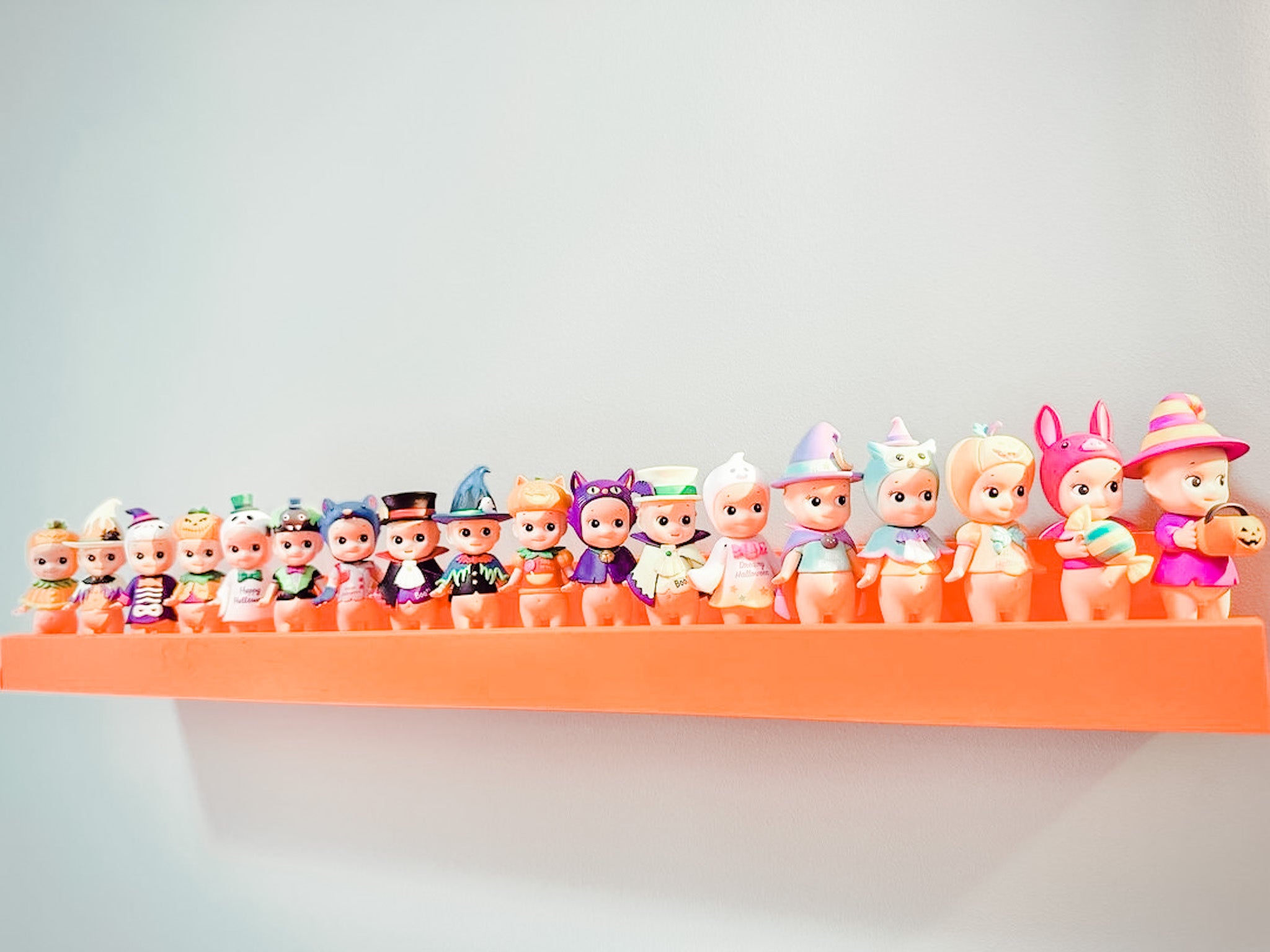 An orange picture ledge full of Sonny Angels