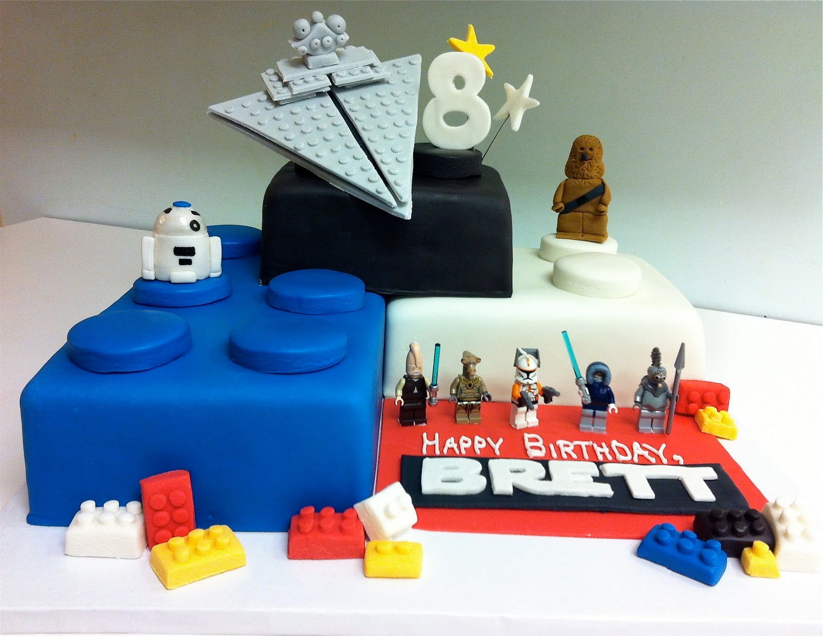 A cake made out of 3 giant LEGO bricks, with Star Wars Minifigures decorating it