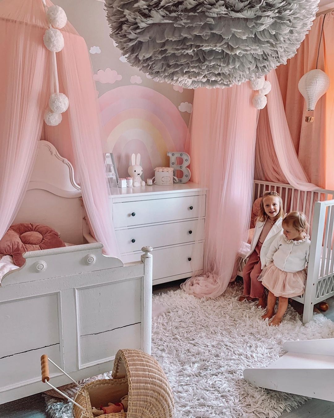 Two little girls in a room with two canopy beds.