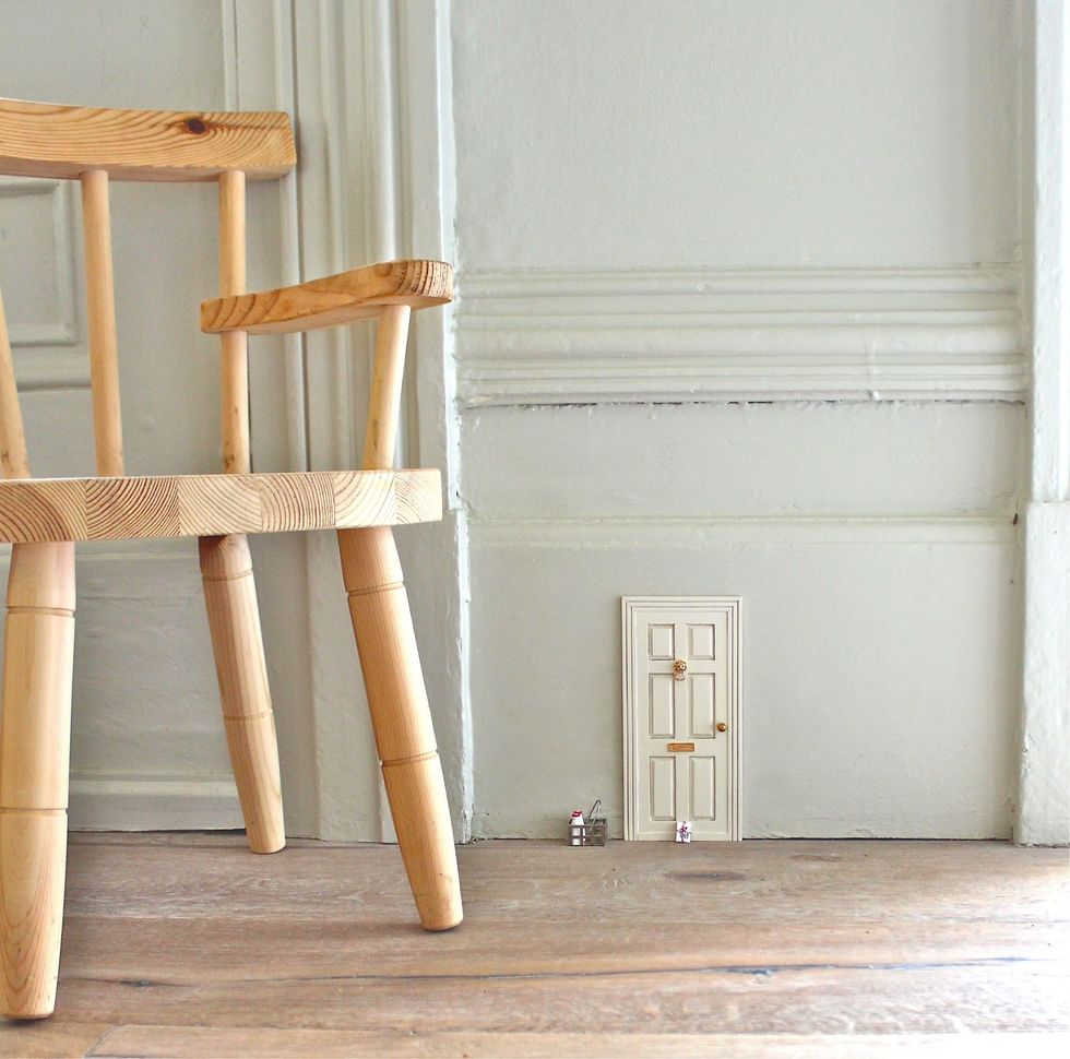 A white fairy door is attached to a white wall.