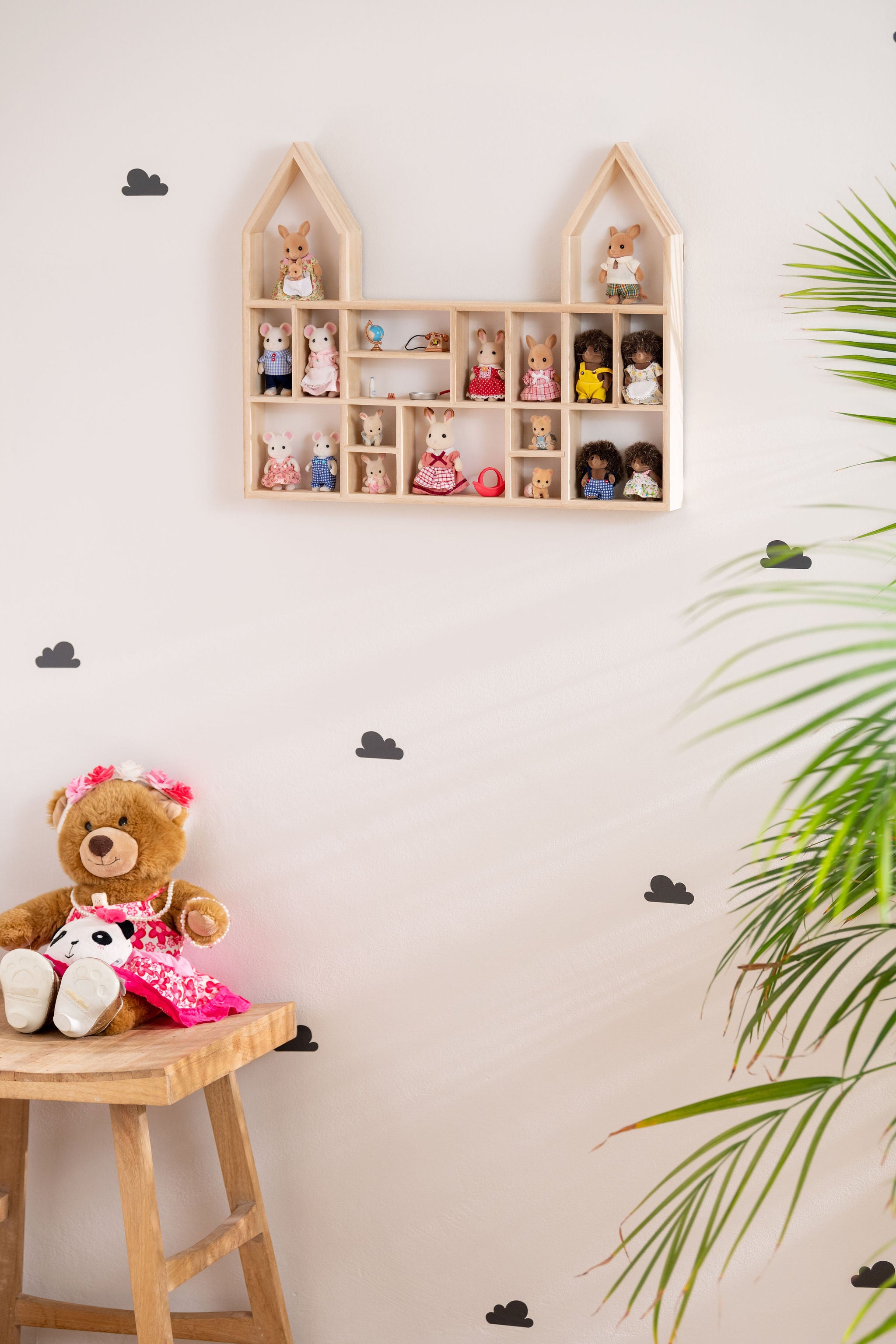 A castle-shaped wooden toy display shelf with Calico Critters hung on the wall