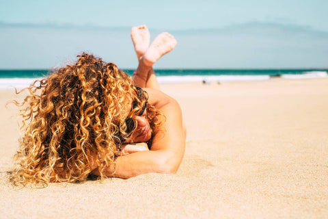 Vrouw met krullen op het strand in de zomer