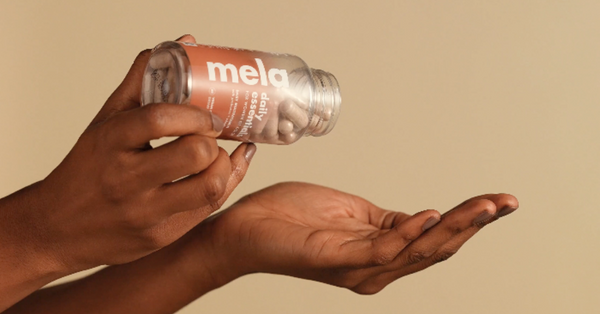 Photo of a Black Woman's hands holding Mela Vitamins Daily Essentials multivitamins.