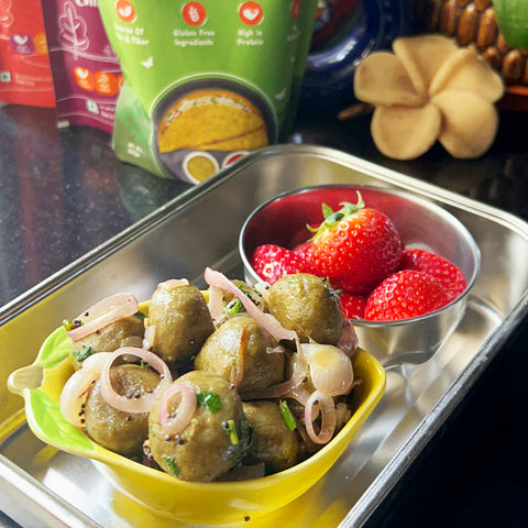 Embracing Healthy Eating with Spinach Balls. An image of green coloured spinach balls and strawberries in a steel tiffin box.