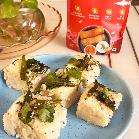 Amaranth Dhokla kept on a blue plate with Gladful Amaranth Dosa Pre-Mix in the background