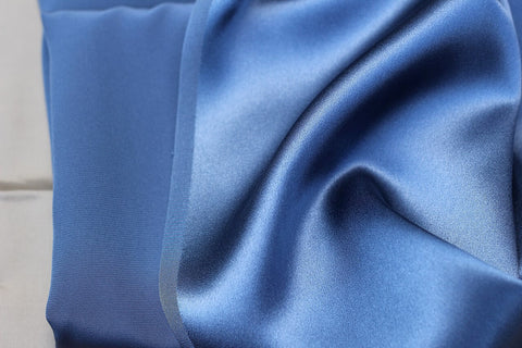 Close-up of blue fabric in a charmeuse weave pattern