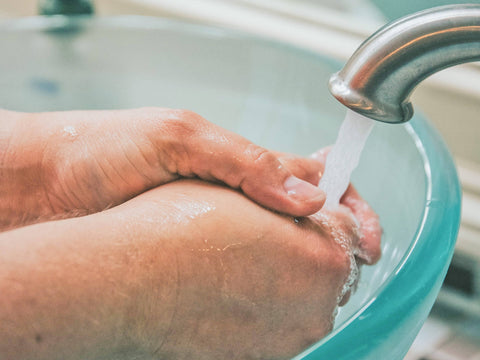 Hand washing in a basin under running water