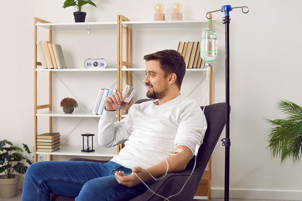 Man drinking water while receiving mobile IV treatment.