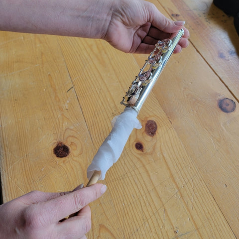 The interior of a flute joint being properly cleaned with a flute rod and swab