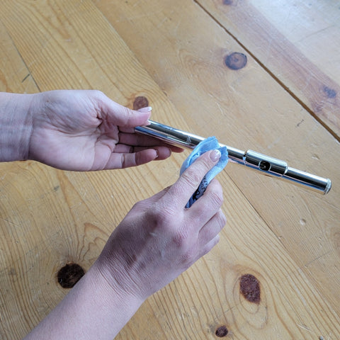 A headjoint of a flute being polished with a clean polish cloth