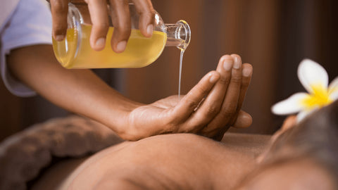 person pouring massage oil into their hand