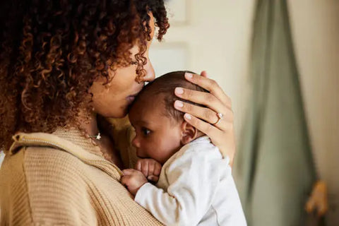 mom holding her baby while kissing it's head