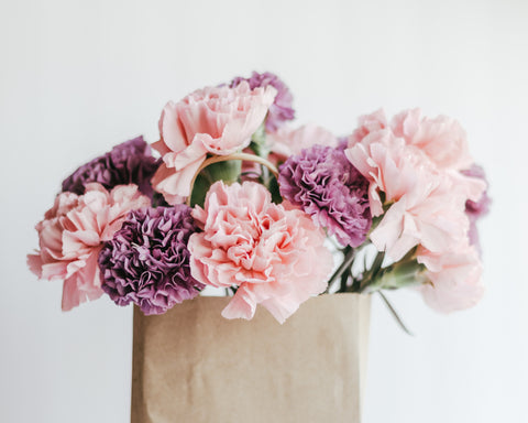 Pink and purple carnations in paper bag