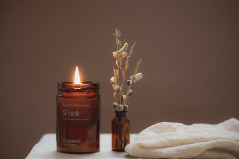 Lit candle next to flower against brown backdrop