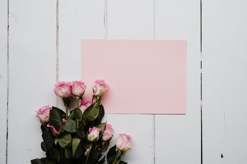 Pink rose bouquet on white wood panel backdrop with pink envelope