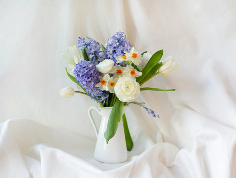 Purple hyacinths and white lilies in white vase
