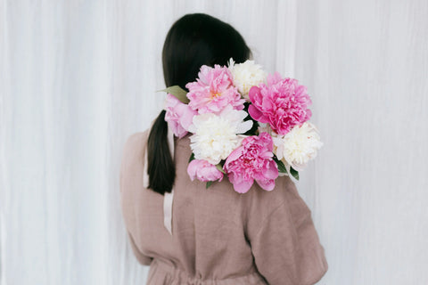 Woman holding pink and white carnation bouquet over shoulder