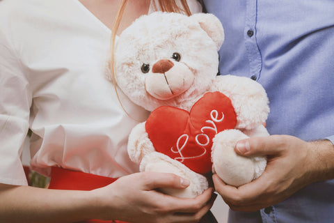 Couple holding a white teddy bear and red heart