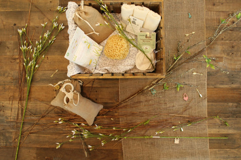 Spa gift basket sitting on wood floor surrounded by flower stems