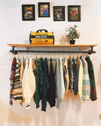 A clothing rack underneath vintage framed photos at Collected Atlanta
