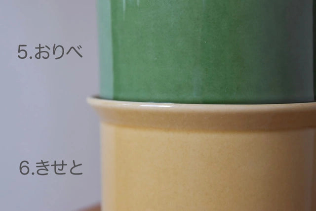 二つのねこ茶碗が積み重ねられた状態のクローズアップ画像。
上部の台座は緑の色合い。「5.おりべ」と記されており、
下部の台座は黄茶色の色合い「6.きせと」と記されています。