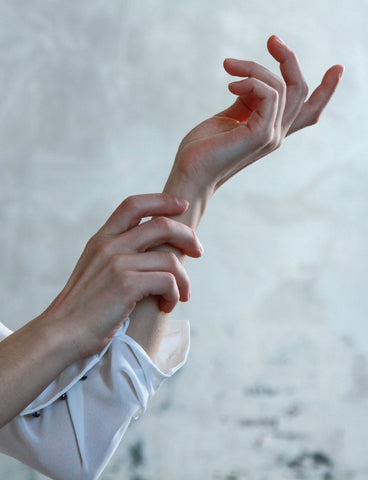 two hands positioned delicately against a light background