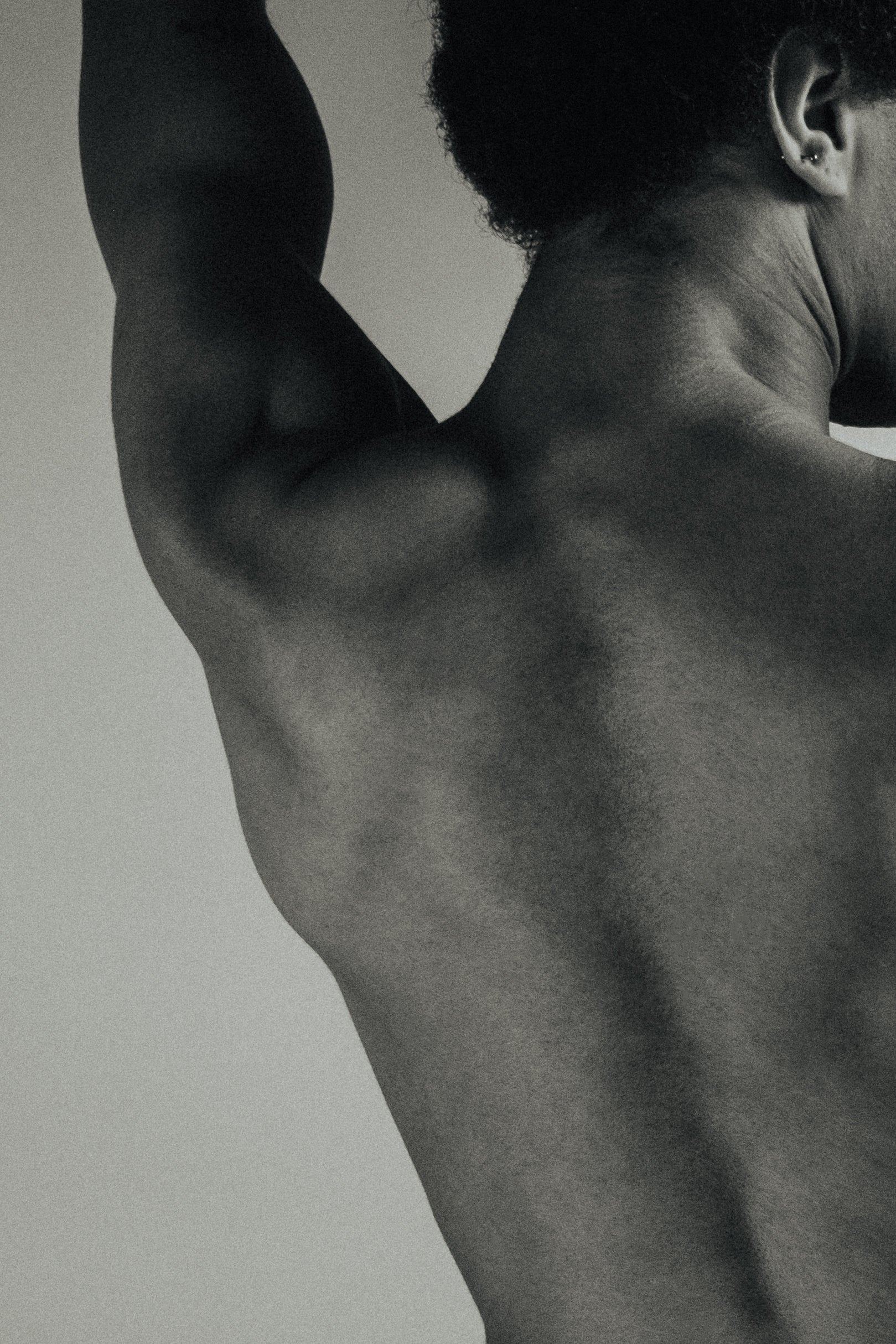 Black and white photo of a person's muscular back and arm.