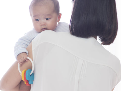 Mother holding child. Child is holding a PlanToys rattle.