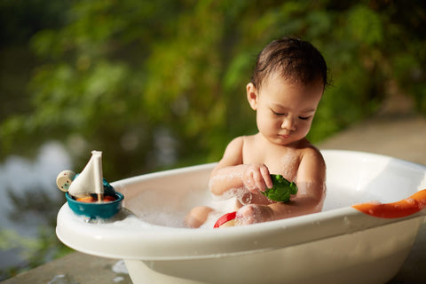 Child playing in bathtub with toys