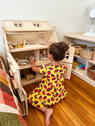 Child playing with wooden dollhouse