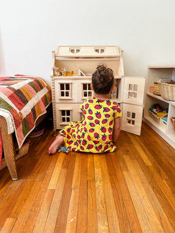 Child playing with wooden dollhouse