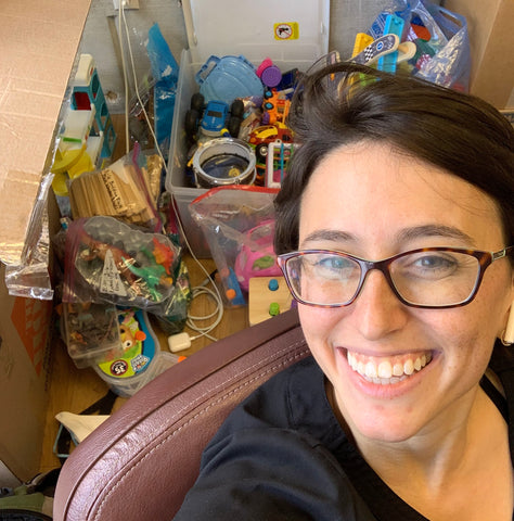 Woman smiling with a donation of toys in the background