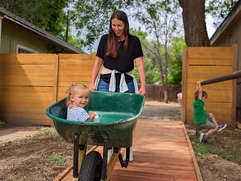 Mother pushing child in a wheelbarrow