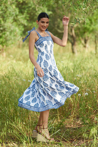 Woman twirling in field with blue pattern dress