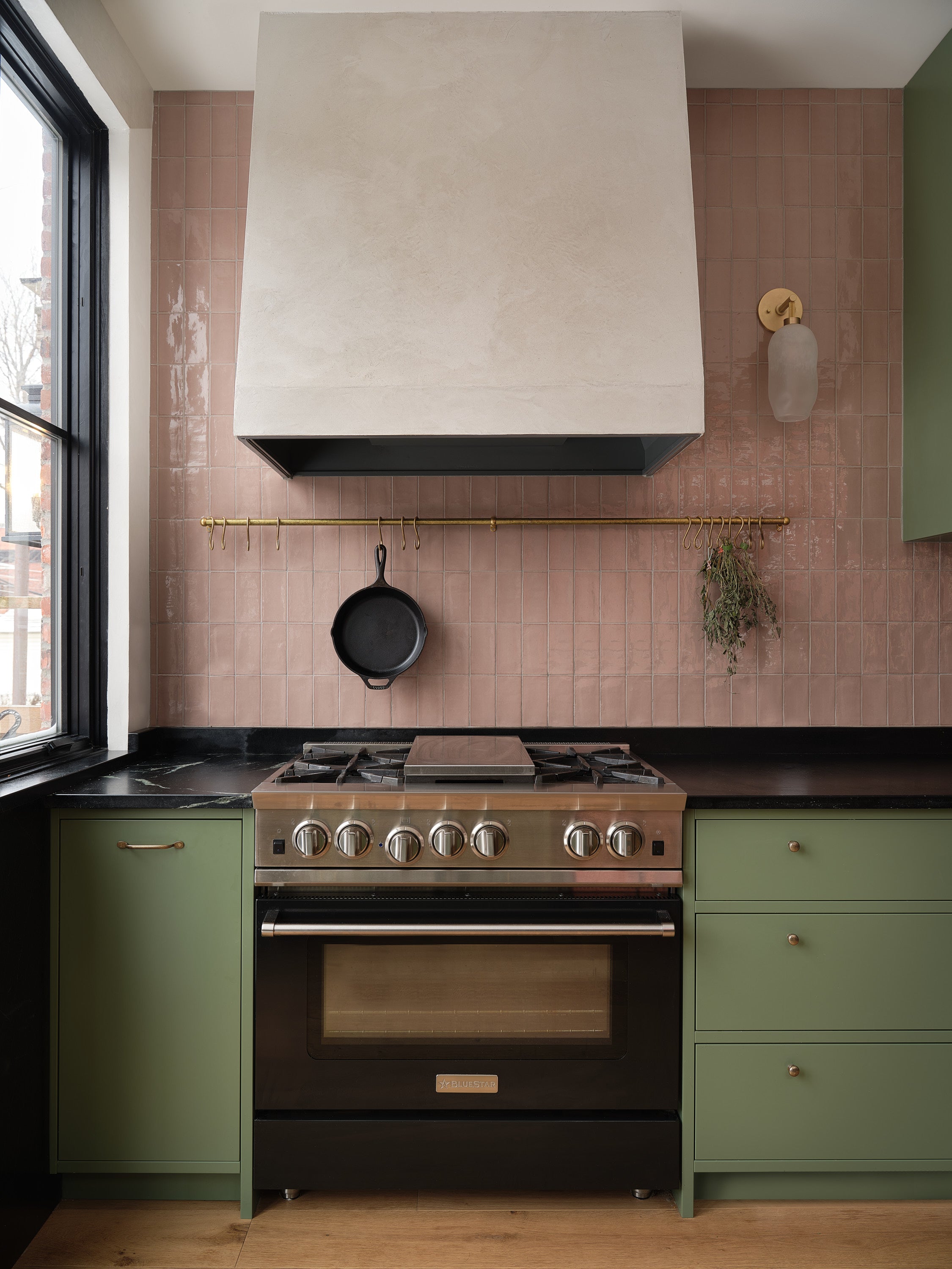 Classic green lacquer kitchen with pink tile backsplash. Small brass details as handles.